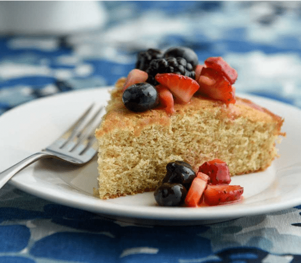 slice of sponge cake topped with cut strawberries, blueberries and blackberries