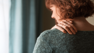 rear view of woman holding her neck and shoulder area