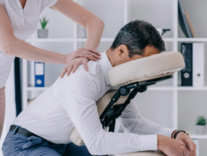 man in clinical office setting, sitting head down in a massage chair receiving a professional back massage