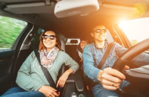 happy family traveling in car viewed from front windshield on a sunny day