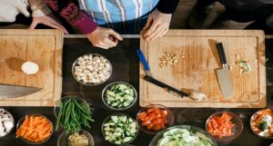 cutting boards with knives and bowls of fresh ingredients around them in a cooking class setting