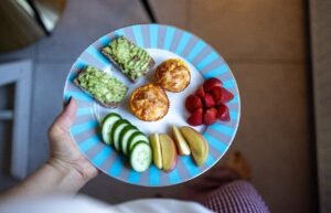 breakfast plate with avocado toast, egg bites, cucumber, apples and strawberries