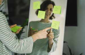 woman looking at herself in full length mirror with reminder post it notes scattered on it