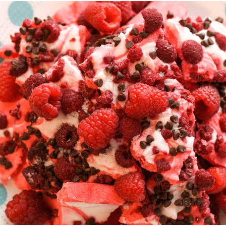 mound of raspberries yogurt and chocolate bark on a festive plate