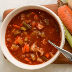 colorful soup in bowl on cutting board with vegetables