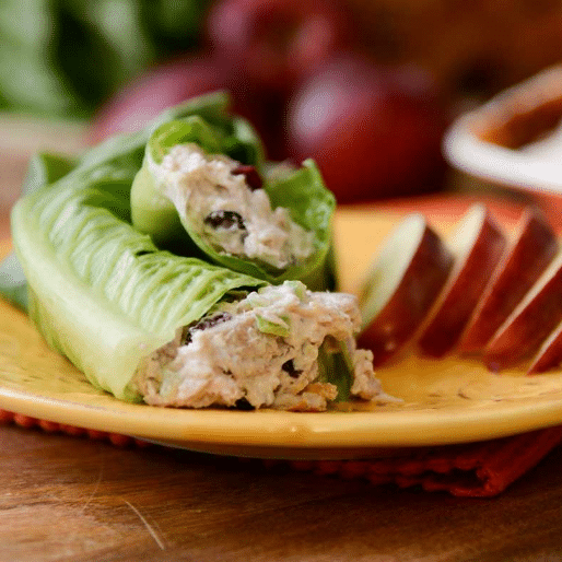 turkey salad wrapped in lettuce on yellow plate with sliced apples