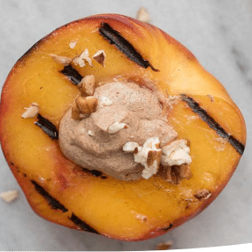Grilled peach topped with honey, cinnamon cream cheese and crushed pecan sprinkles
