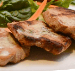 Grilled pork chops with mustard sauce, a salad in the background