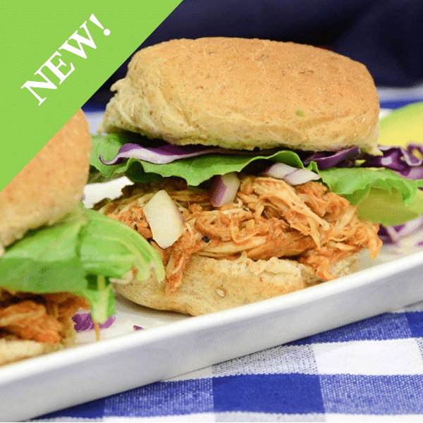 Pulled chicken sliders with red onion, red rabbage and greens on long white plate at blue gingham clad outdoor table