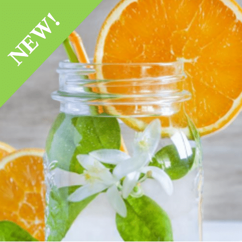 mason jar filled with water, white flowers with leaves, orange and green straws and garnished on the rim with large thin orange circle slice