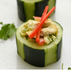 slice of cucumber topped with chicken salad and red garnish